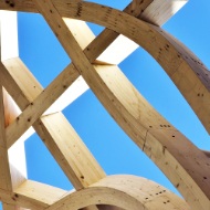 Curved timber beams against a blue sky