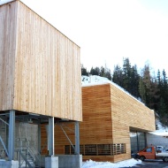 100 m³ timber modular silo with steel substructure, alongside a maintenance depot building with identical facade
