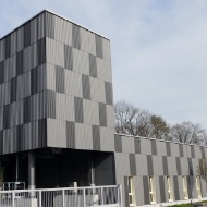 Silo modulaire architectural de 250 m³ avec façade en bois à carreaux gris clair et gris foncé, intégré visuellement dans un plus grand complexe immobilier