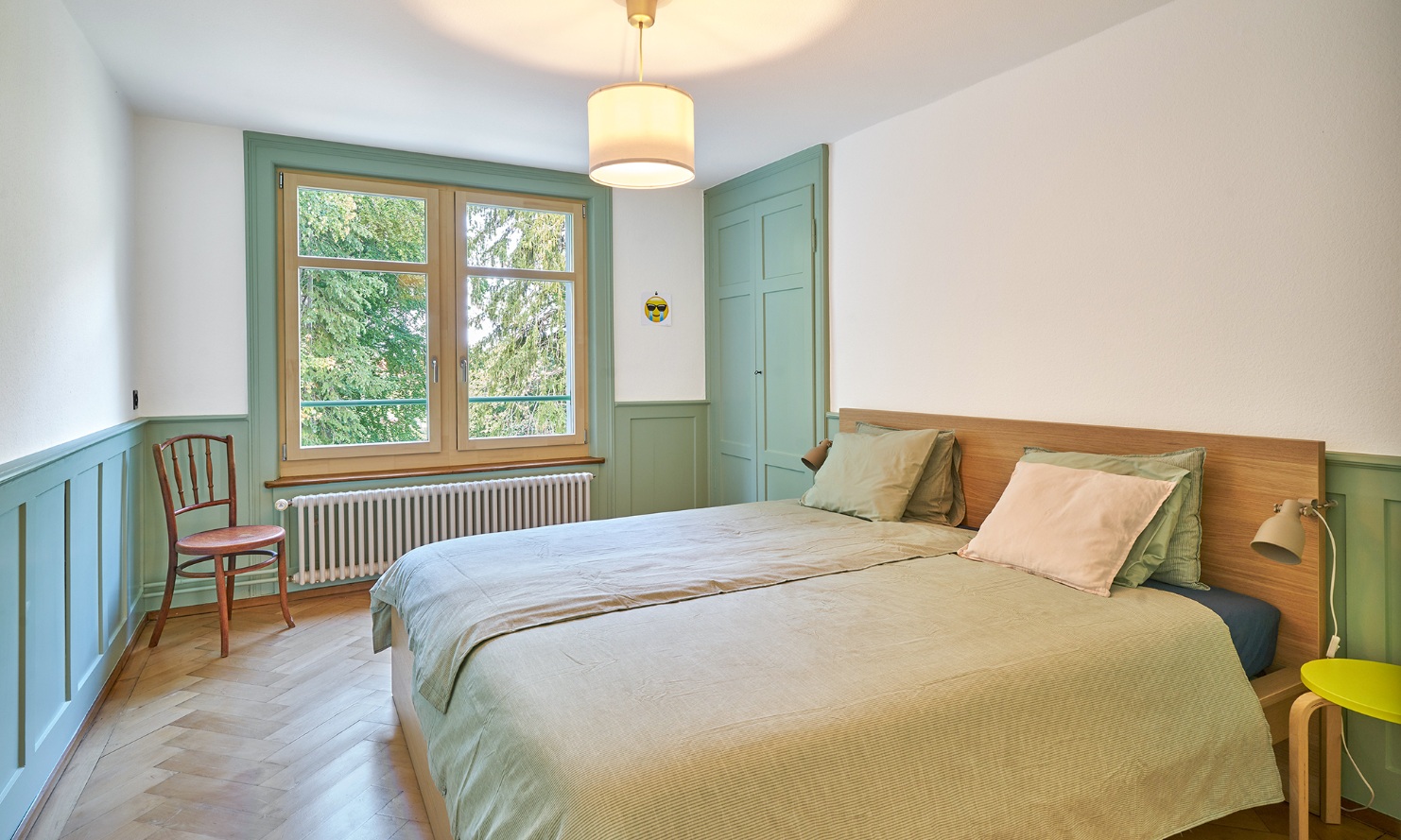Bedroom with wooden floor and light-green accenting features