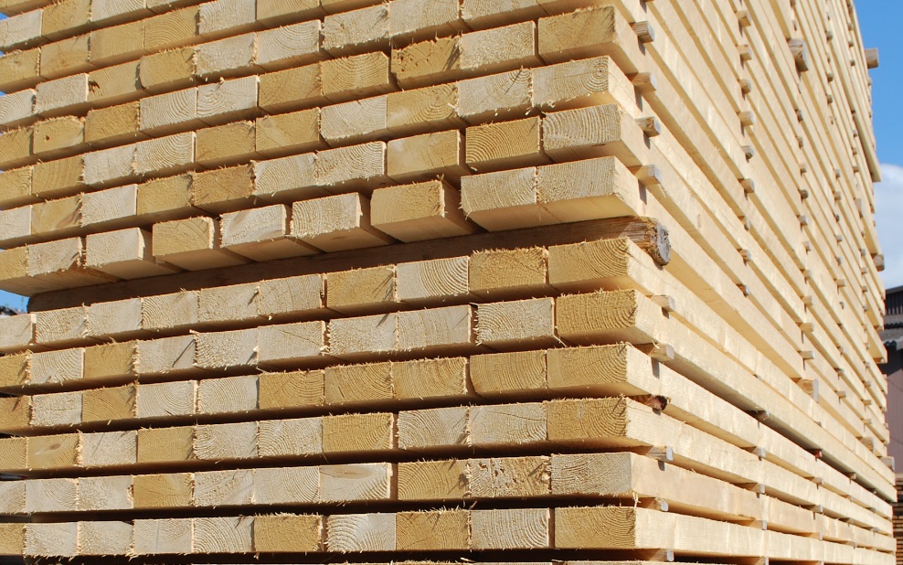 Stack of square timber in the open air, with blue sky in the background