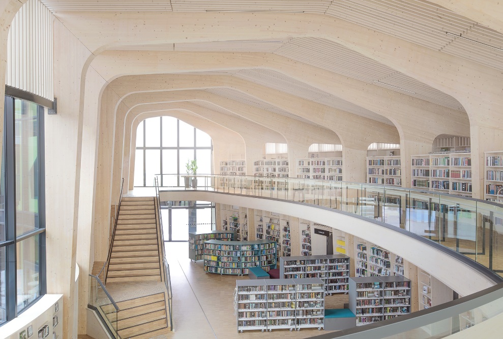 View from the balcony into the large, bright space with staircase and bookshelves 